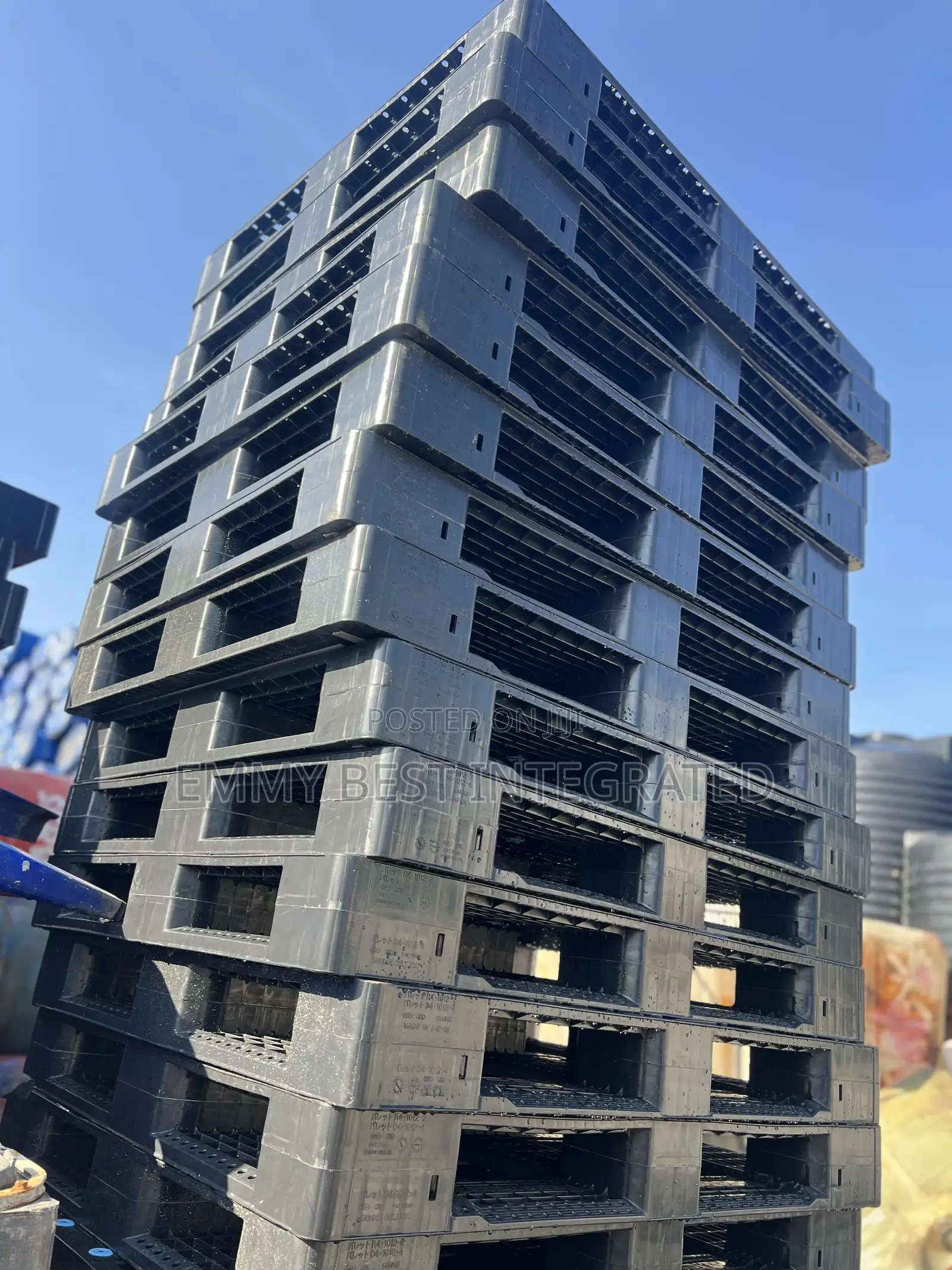 Tall Stack Of Black Plastic Pallets.