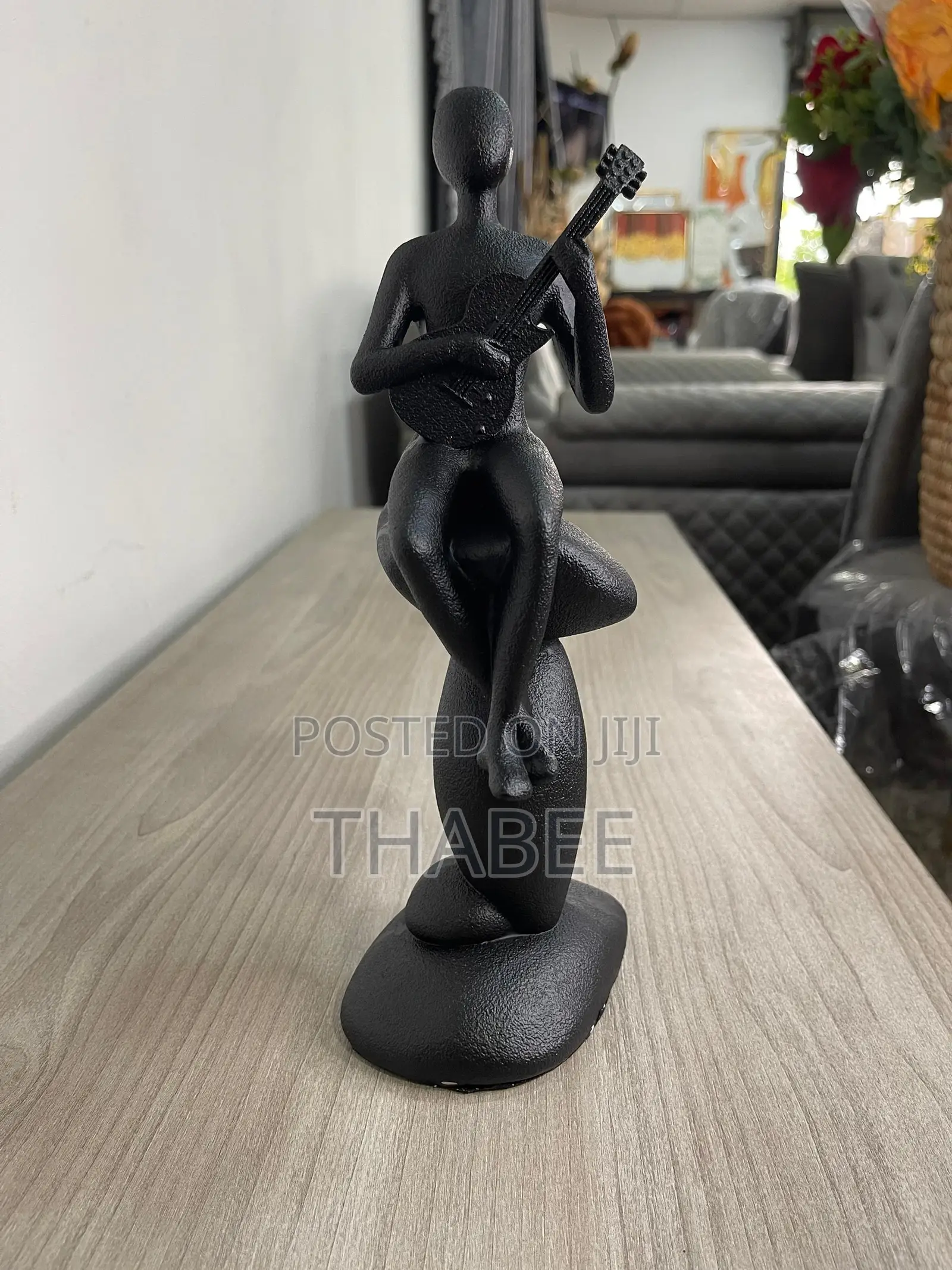 Black Figurine Man Sitting On A Rock With Guiter
