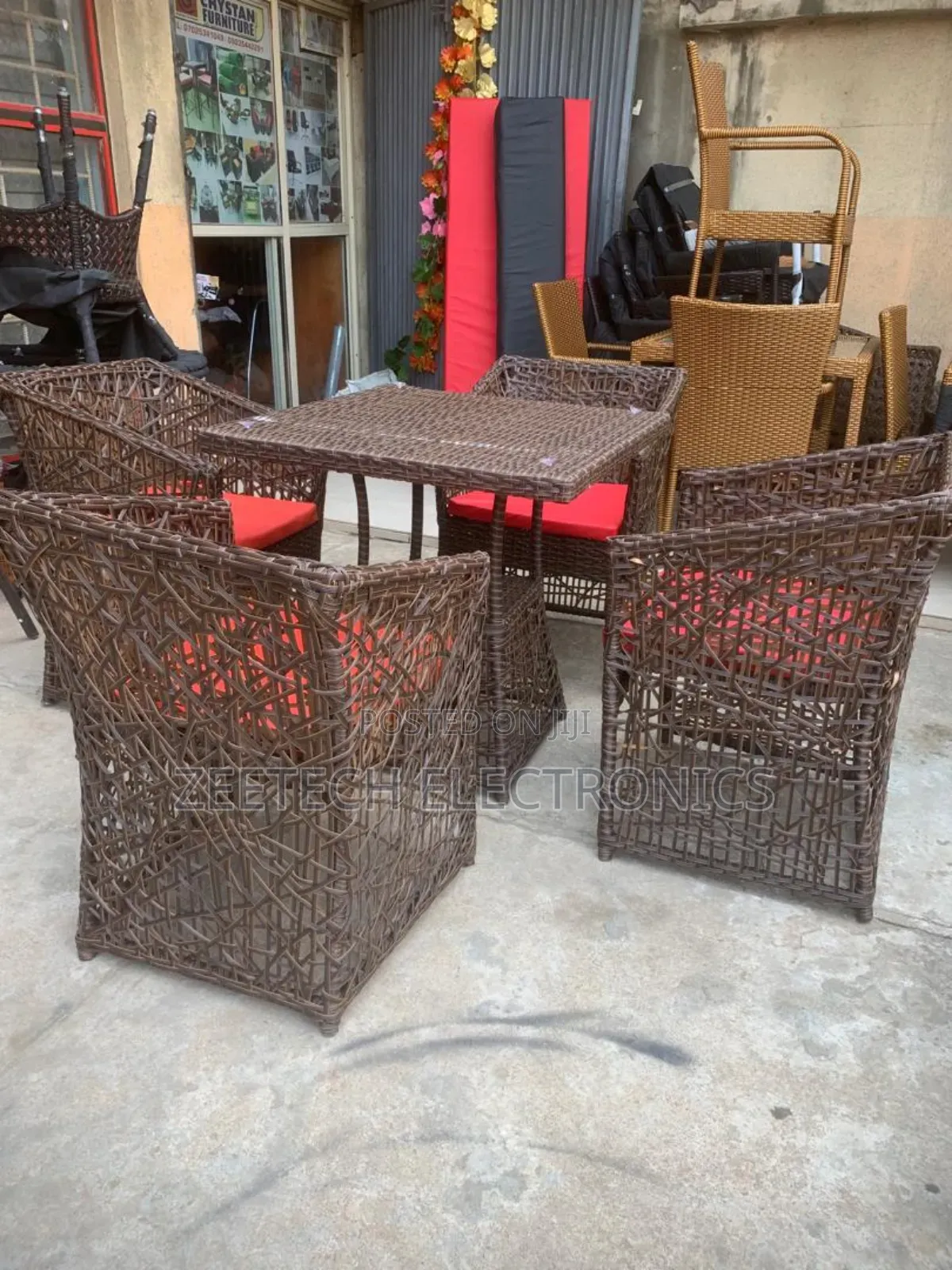 Brown 4-Seater Rattan Dining Table and Chairs Set With Red Cushions.