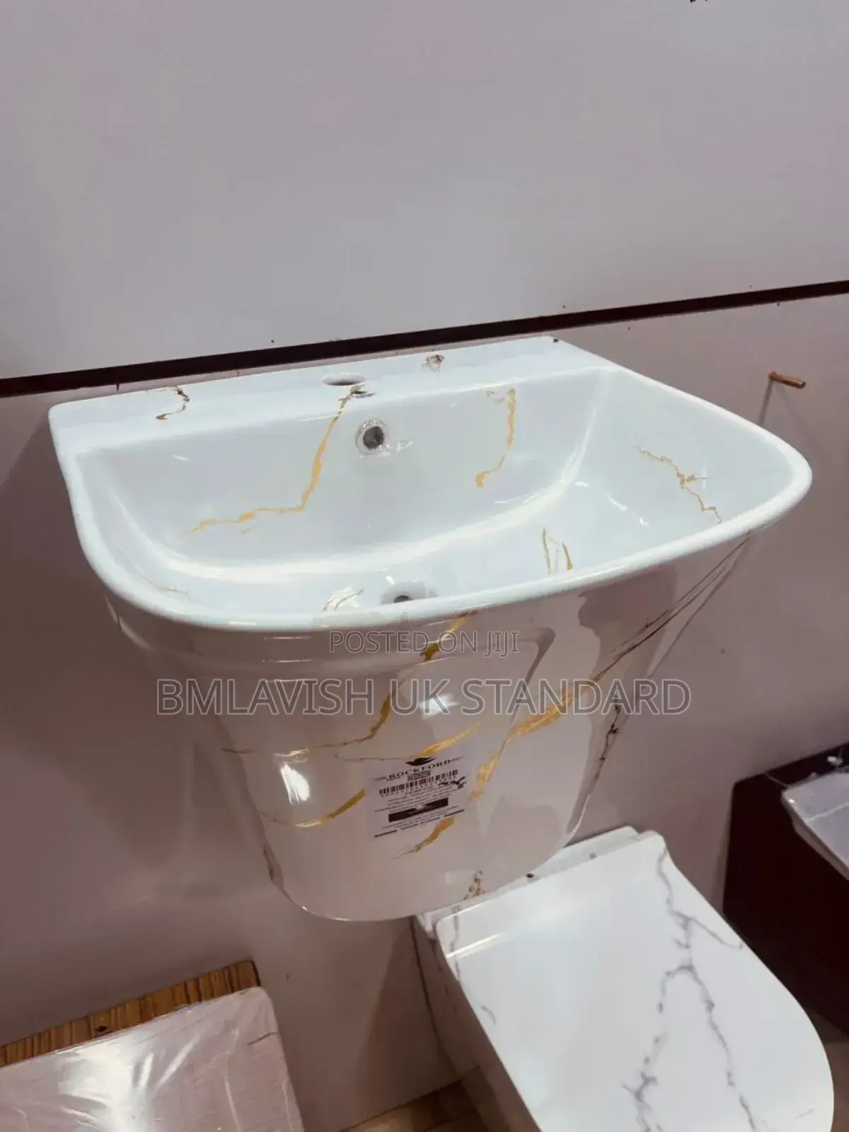 Wall-Mounted Wash Basin With a White and Gold Marble-Style Finish.