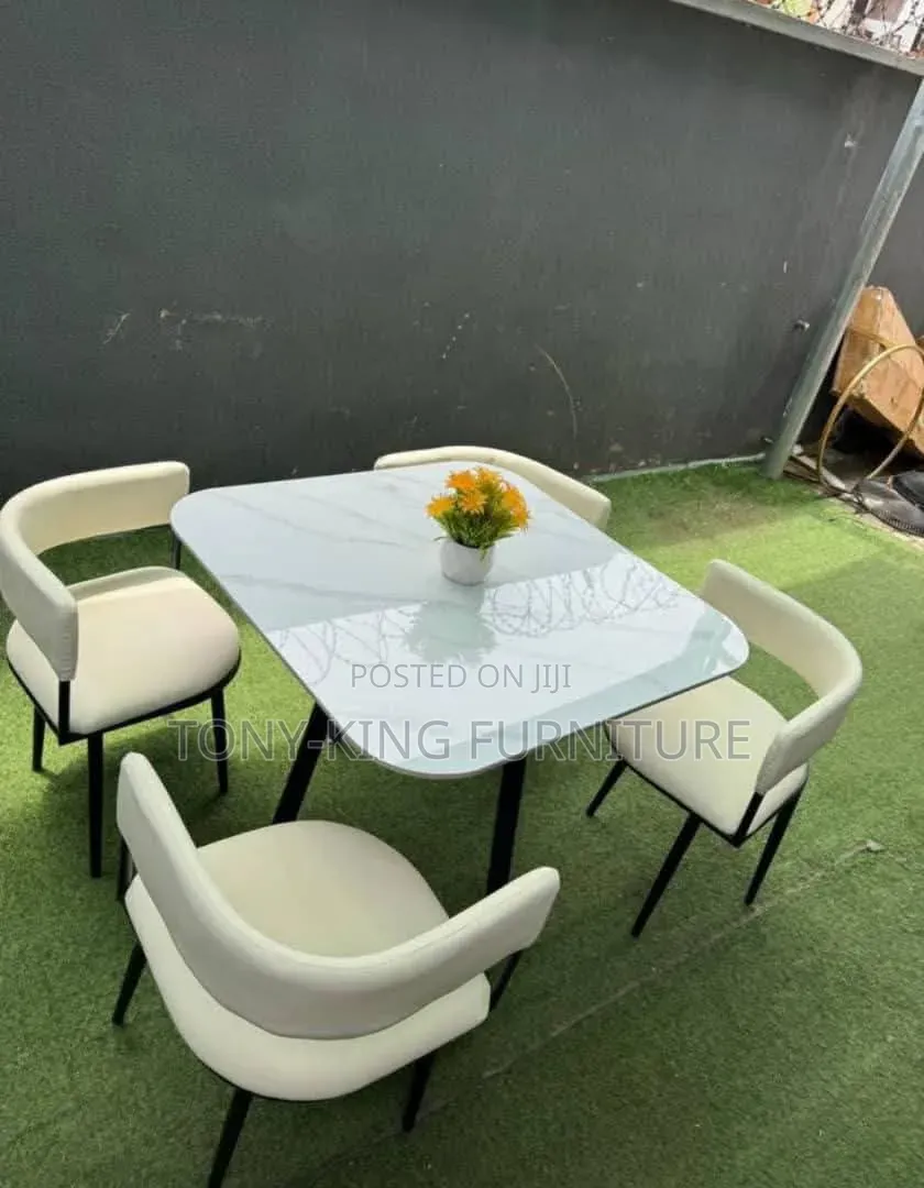 Modern Dining Table With A Marble Top And Black Upholstered Chairs.