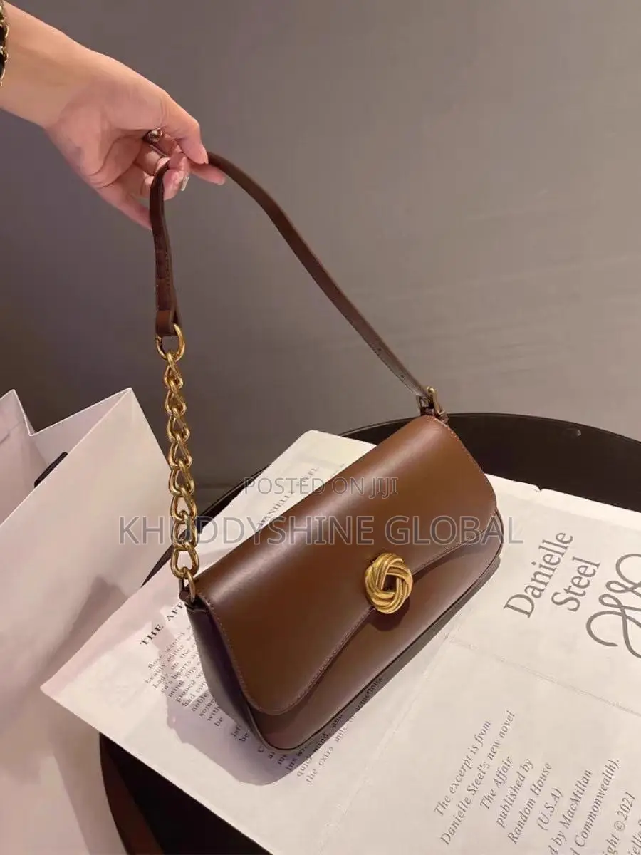 Leather Baguette Shoulder Bag Features a Distinctive Gold-Toned Twist